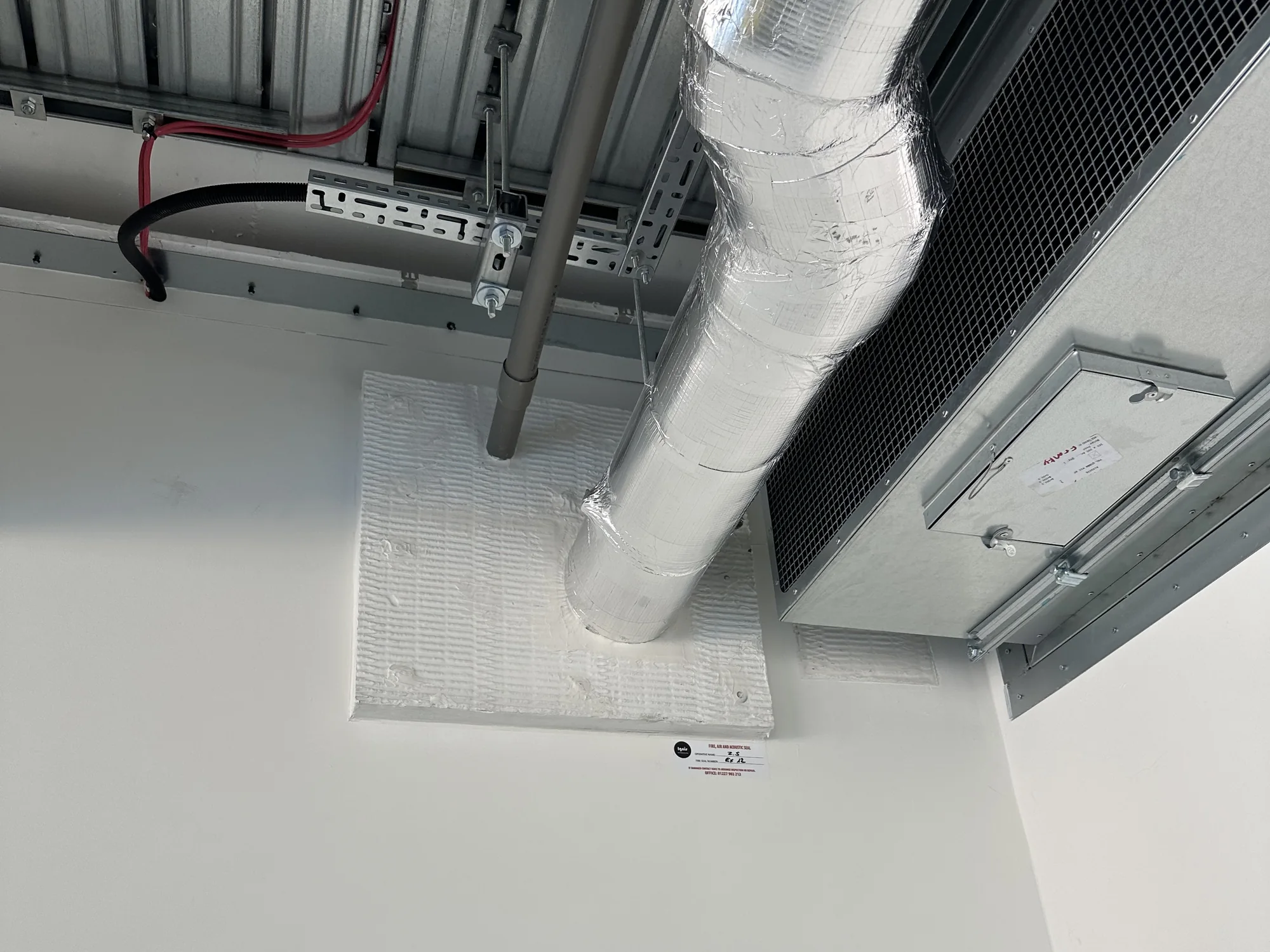 Illustrative service image: a foil-insulated duct and smaller services passing through a white sealed wall opening.