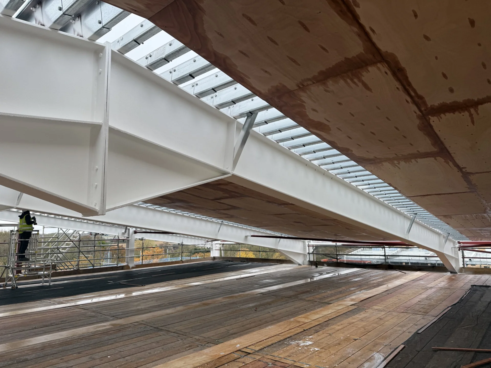 Illustrative service image: white-coated structural steel beams beneath a timber deck.